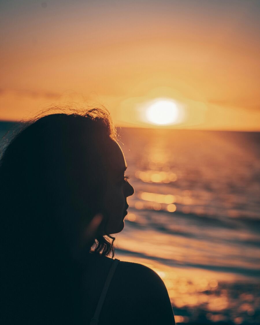 Silhouette of a person looking toward the ocean at sunset